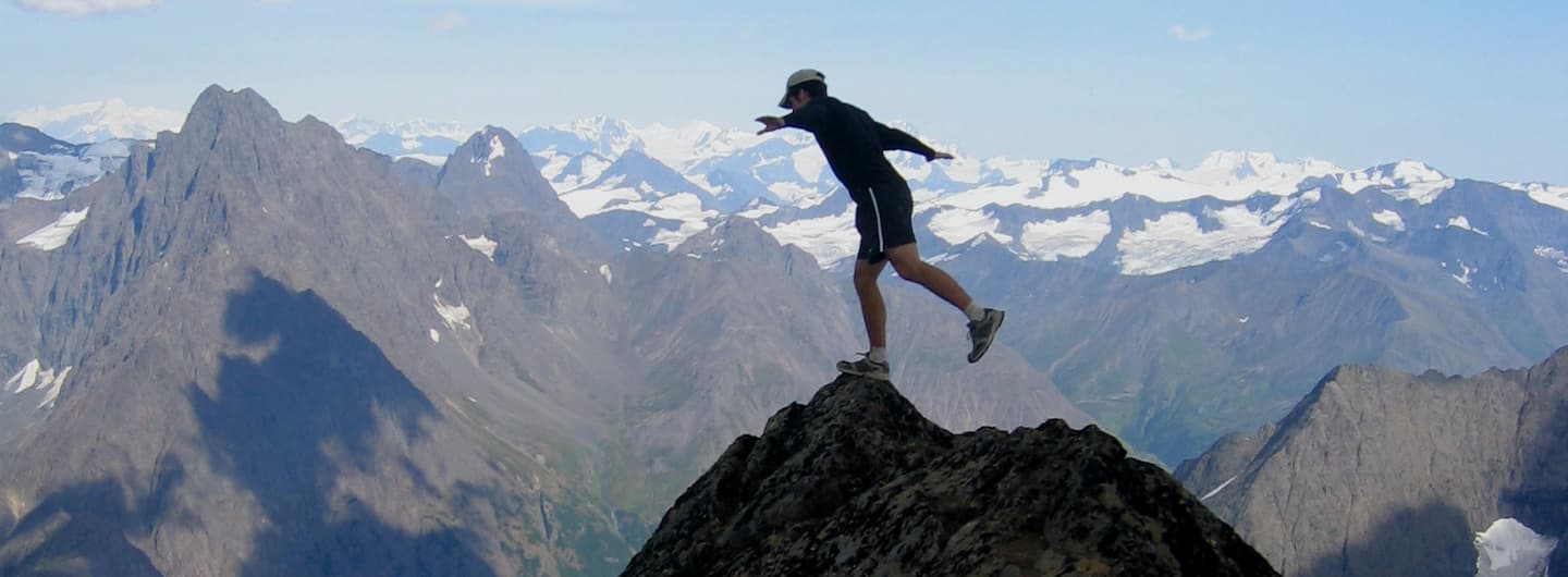 guy balancing on a mountain peak